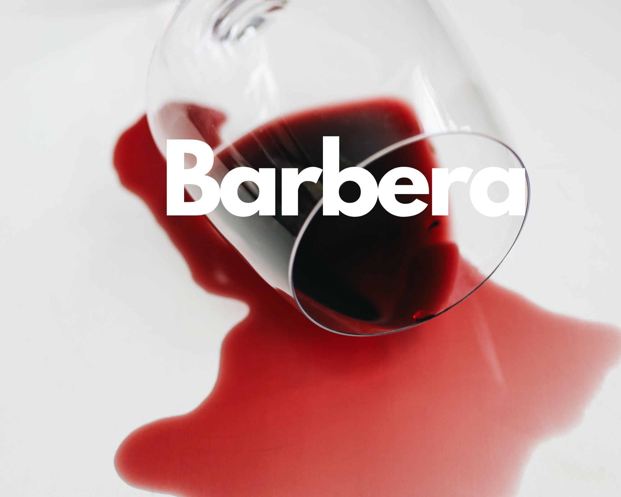 A glass of spilled red wine in a white background, Italian grape varieties