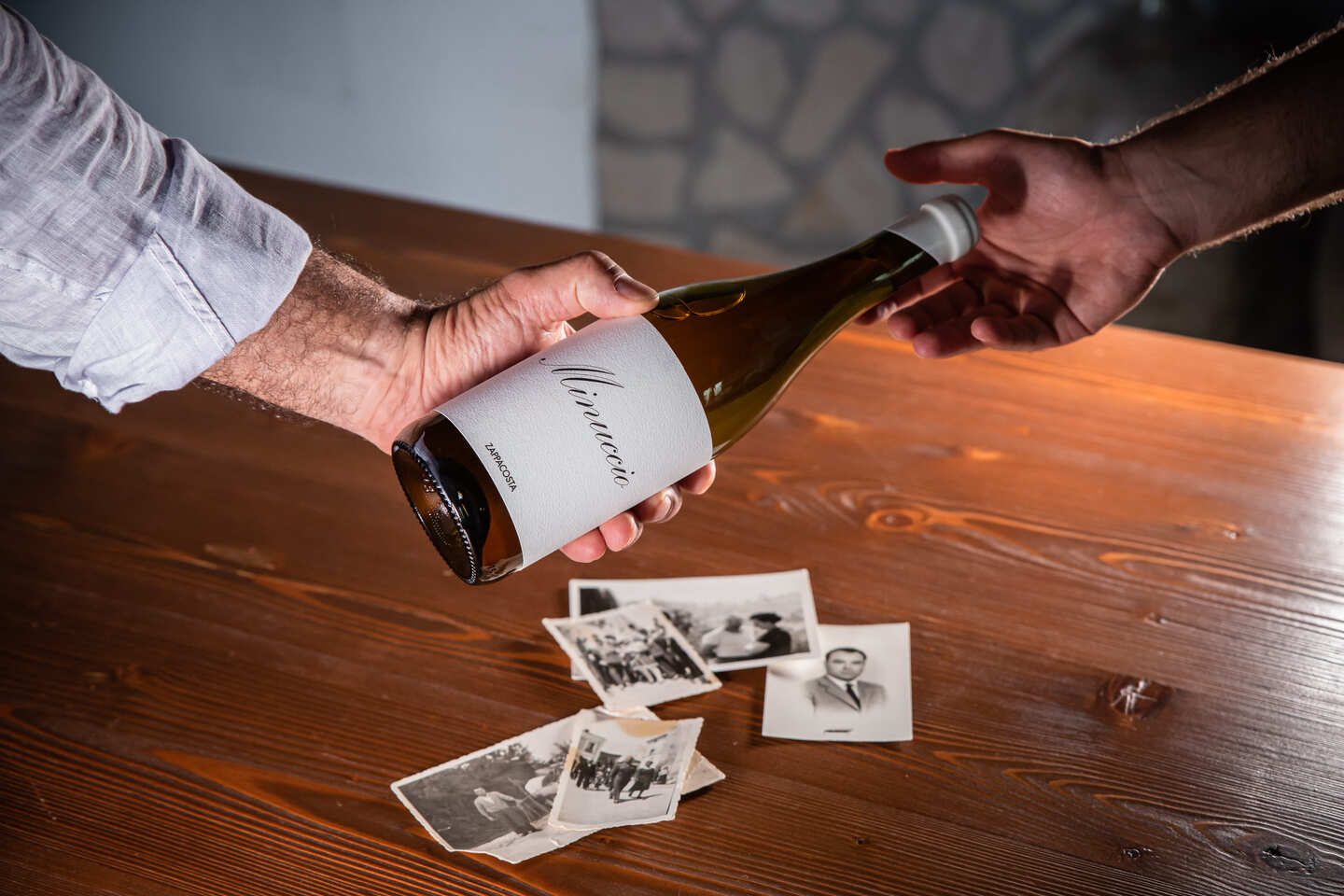 A bottle of wine, above of a wooden table and a few photos